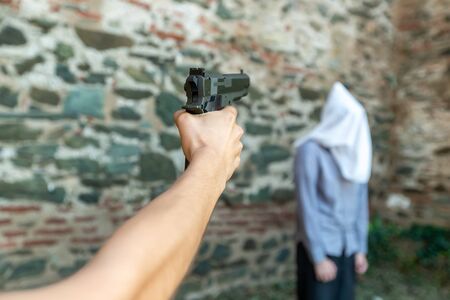 a hand with a gun marks a man with a hood on his head. selective focusの写真素材