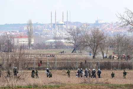 Kastanies, Evros, Greece - March 2, 2020: Greek police and soldiers in front of a fence trying to deter migrants as they attempt to enter Greece from Turkey at the Greek-Turkish border in Kastaniesのeditorial素材