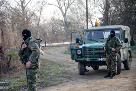 Kastanies, Evros, Greece - March 1, 2020: Greek soldiers guard as migrants gather near the Kastanies border gate at the Greek-Turkish borderのeditorial素材