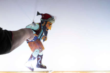 Thessaloniki, Greece - March 9, 2020: unidentified performers playing with the main character (Karagiozis) in the Greek shadow theatre behind the cotton screen during folk show.のeditorial素材