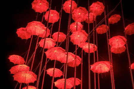Thessaloniki - Greece, April 29, 2021: The sculpture "Umbrellas" by late Greek artist George Zongolopoulos lighting in red for the Epitafios procession.のeditorial素材