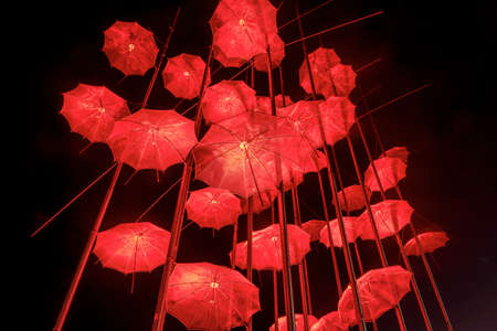 Thessaloniki - Greece, April 29, 2021: The sculpture "Umbrellas" by late Greek artist George Zongolopoulos lighting in red for the Epitafios procession.のeditorial素材