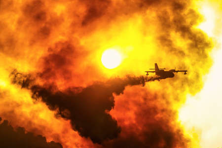 A firefighting plane releases its load of water as it tries to extinguish a fire at sunrise near the Ancient Olympia on August 5, 2021 in Peloponnese, Greeceの写真素材
