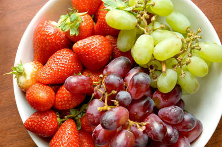 Grapes and strawberries on the white bowl.の写真素材
