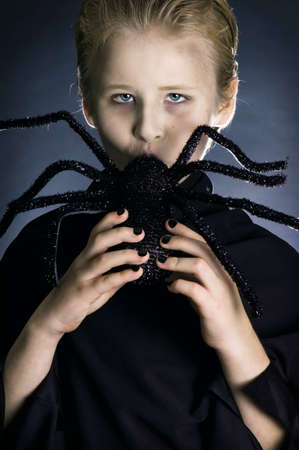 Boy dressed up as a vampire for halloween party kissing/sucking giant spider.の写真素材