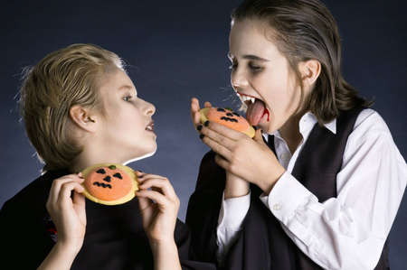Is really his cookie better than mine? Two boys dressed up as vampires with Halloween biscuitsの写真素材