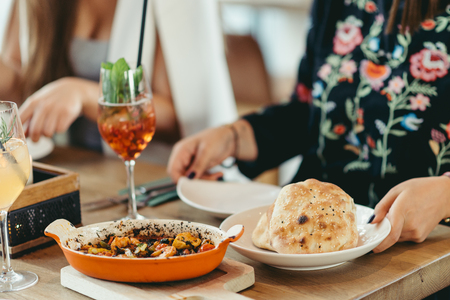 covered Turkish restaurant table with a shrimp and veggies casserole and  cocktailの写真素材
