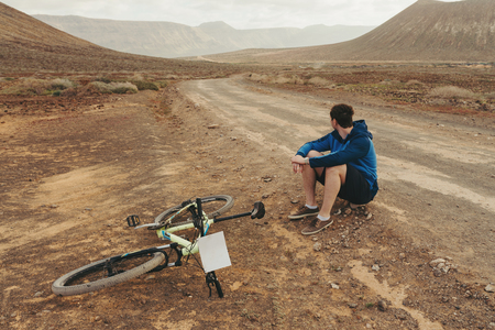 Handsome man in casual outfit sitting near of mountain bike on the road , Canarian islandの写真素材