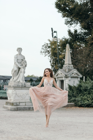 beautiful woman in long rose evening dress walking path in park . Fashion style portrait of gorgeous beautiful girl outdoorsの写真素材