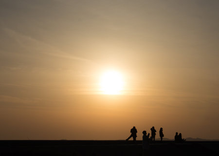 Silhouette of a group of people watching the sunsetの写真素材