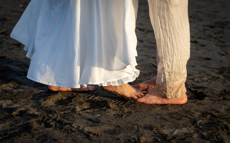Legs of a man and a woman in white clothes on the beachの写真素材