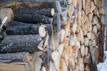 Sawn logs covered in snow in winter season, outdoors stacked industrial woods material, stack of...
