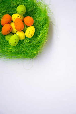 Green nest with colorful Easter eggs decoration on light purple background. Easter concept, holiday...