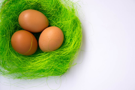 Green nest with three Easter eggs decoration - Easter concept, holiday tradition top view, close-up with copy space for text on white backgroundの写真素材