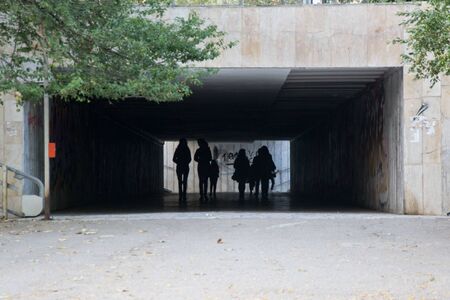 Varna, Bulgaria, 10/27, 2019 - People walking through a dark underpass with glowing end, underground passage, blurred people silhouettesのeditorial素材