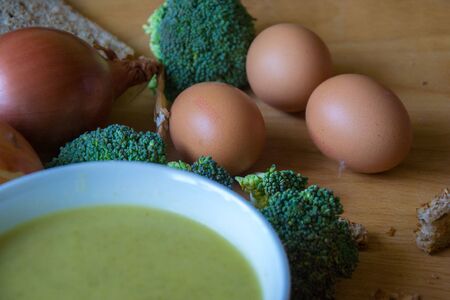 Close-up of healthy lunch, vegetable soup from broccoli, and bread, onion, eggs in the back, food on a wooden table, healthy eatingの写真素材