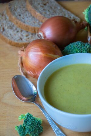 Close-up of healthy lunch, vegetable soup from broccoli, and bread, onion, eggs in the back, food on a wooden table, healthy eatingの写真素材