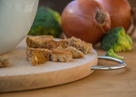 Close-up of healthy vegetarian food, vegetables - green broccoli, bread and onions in the kitchen placed on wooden tableの写真素材