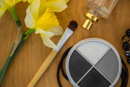 Beautiful yellow daffodils and set of decorative cosmetics, brushes and lipstick, jewelry, perfume, make up and girly stuff, flat lay, top viewの写真素材