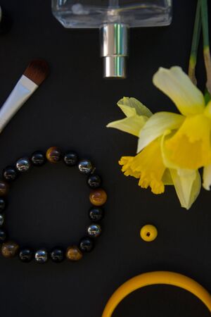 Beautiful yellow daffodils and set of decorative cosmetics, brushes and lipstick, jewelry, perfume, make up and girly stuff, flat lay, top viewの写真素材