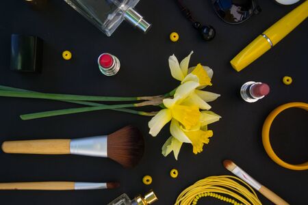 Beautiful yellow daffodils and set of decorative cosmetics, brushes and lipstick, jewelry, perfume, make up and girly stuff, flat lay, top viewの写真素材