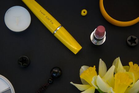 Beautiful yellow daffodils and set of decorative cosmetics, brushes and lipstick, jewelry, perfume, make up and girly stuff, flat lay, top viewの写真素材