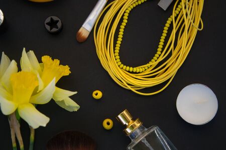 Beautiful yellow daffodils and set of decorative cosmetics, brushes and lipstick, jewelry, perfume, make up and girly stuff, flat lay, top viewの写真素材