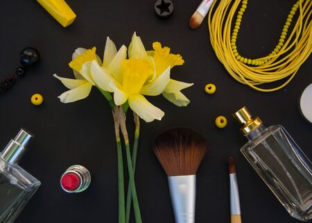Beautiful yellow daffodils and set of decorative cosmetics, brushes and lipstick, jewelry, perfume,...