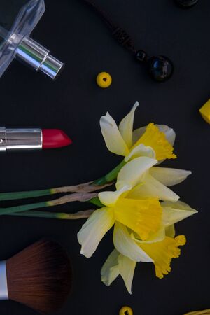 Beautiful yellow daffodils and set of decorative cosmetics, brushes and lipstick, jewelry, perfume, make up and girly stuff, flat lay, top viewの写真素材