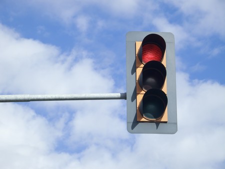Red traffic light on sky