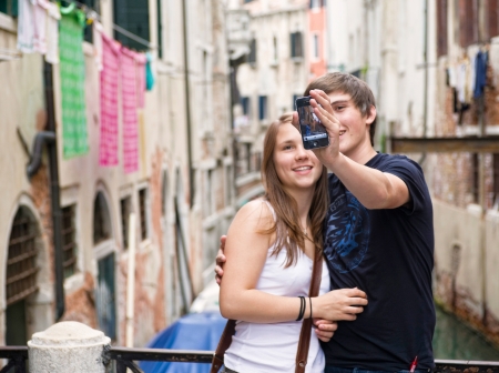 Venice, Italy - September 20, 2011: Couple of tourists during a self-portrait with an iPhone. Shot along a narrow alley in Venice, Italy.のeditorial素材