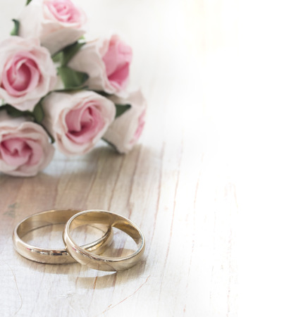 Wedding rings and beautiful roses on a wooden tableの写真素材