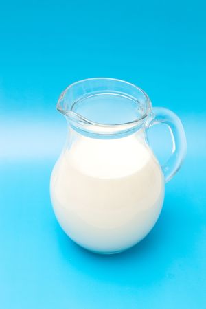 Glass jug with cold milk on blue backgroundの写真素材