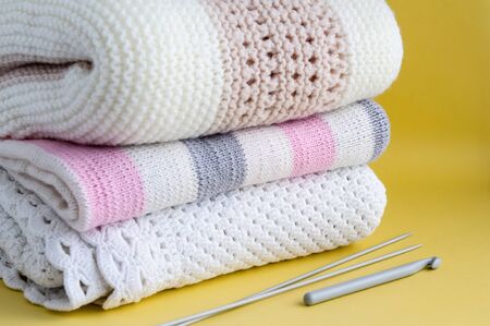 Knitted warm plaids of light color, bedding on a yellow background. Cozy background with copy space,...