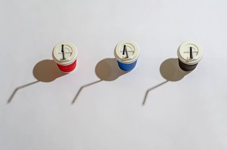 Bright paper coffee containers with a white lid and brown plastic tubes and shadows on a white...