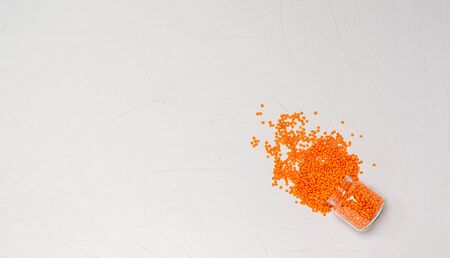Dry groats of orange lentils for vegans in a glass jar on a white background. Copy space. Place for text. Flat lay. Healthy foods high in protein and carbohydrates. View from above.の写真素材