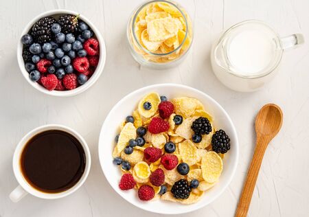 Ingredients for a healthy breakfast - cornflakes, berries, milk and coffee on a white background. Copy space for your text, flat lay, healthy snacks, quick breakfast. View from above.の写真素材