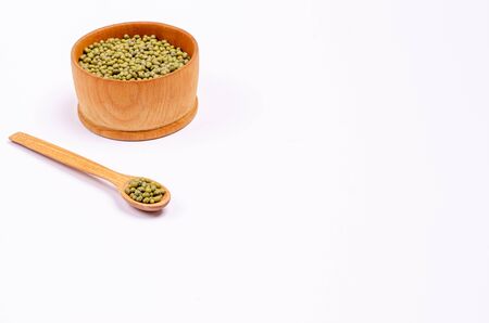 Dry green lentils for vegans in a wooden spoon and bowl on a white background, copy space, place for text. Healthy foods high in protein and carbohydrates. Close-up. Horizontal orientation.の写真素材