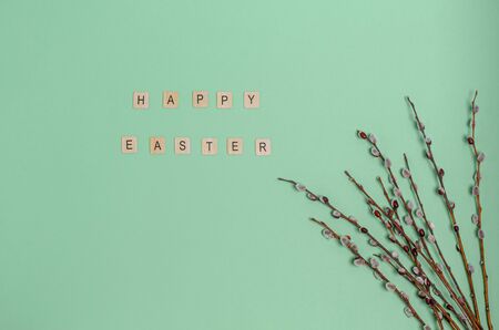 Willow twigs and the word Happy Easter on a green background, copy space, flat lay. Place for text. The concept of the holiday, spring. View from above.の写真素材