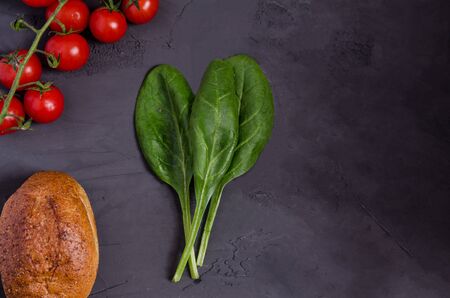 Tomatoes, spinach, buckwheat without yeast on a dark background, copy space. Flat lay. Healthy snack, proper nutrition. View from above.の写真素材