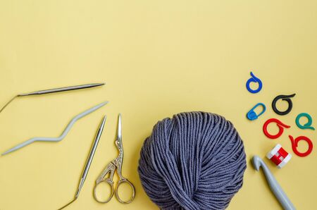 Knitting tools on a yellow background. Skein of thread, pins, markers, row counter, knitting needles...