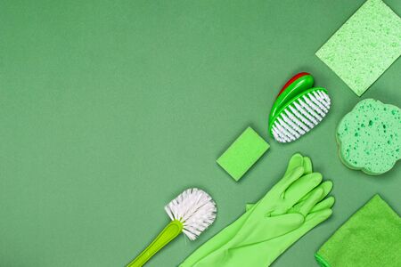 The concept of cleaning, cleanliness and hygiene. Cleaning supplies - rag, brush, washcloths, sponge mittens, green background. View from above. Flat lay, copy space.の写真素材