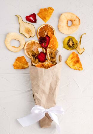 Fruit chips in an envelope from kraft paper on a white background. Healthy and healthy snack, healthy lifestyle, natural sweetness, dessert. View from above. Flat lay, copy spaceの写真素材