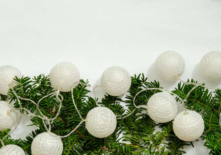 White garland in the form of large balls of thin threads on the branches of spruce with space for copy space and a flat lay on a white background. The concept of warmth, comfort, holiday.の写真素材