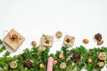 Fir branches, gift boxes, star anise anise, dry orange slices, decorative balls and nuts on a white background. Copy space, flat lay.の写真素材