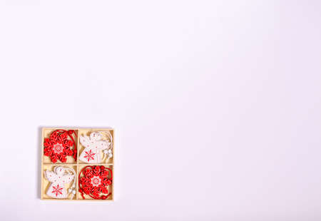 Wooden toys of white and red color in the form of snowflakes and angels in a box on a white background. Banner, form for a postcard. Copy space, flat lay. New Year, Christmas, 2021. Top view.の写真素材