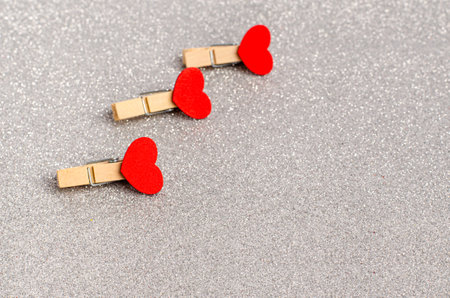 Decorative clothespins with red hearts hang on a clothesline for Valentine's Day on a white...