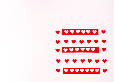 Decorative clothespins with red hearts hang on a clothesline for Valentine's Day on a white...