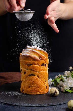 The cake is decorated with white sugar icing and pastry sprinkles on a dark background. Traditional seasonal baked goods in spring. Celebrating the holiday of Easter. Close-up.の写真素材