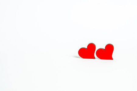 Red heart in a female hand near a wooden calendar with the date of February 14 on a white background. Love concept, copy space, flat lay, place for text, banner, top view.の写真素材